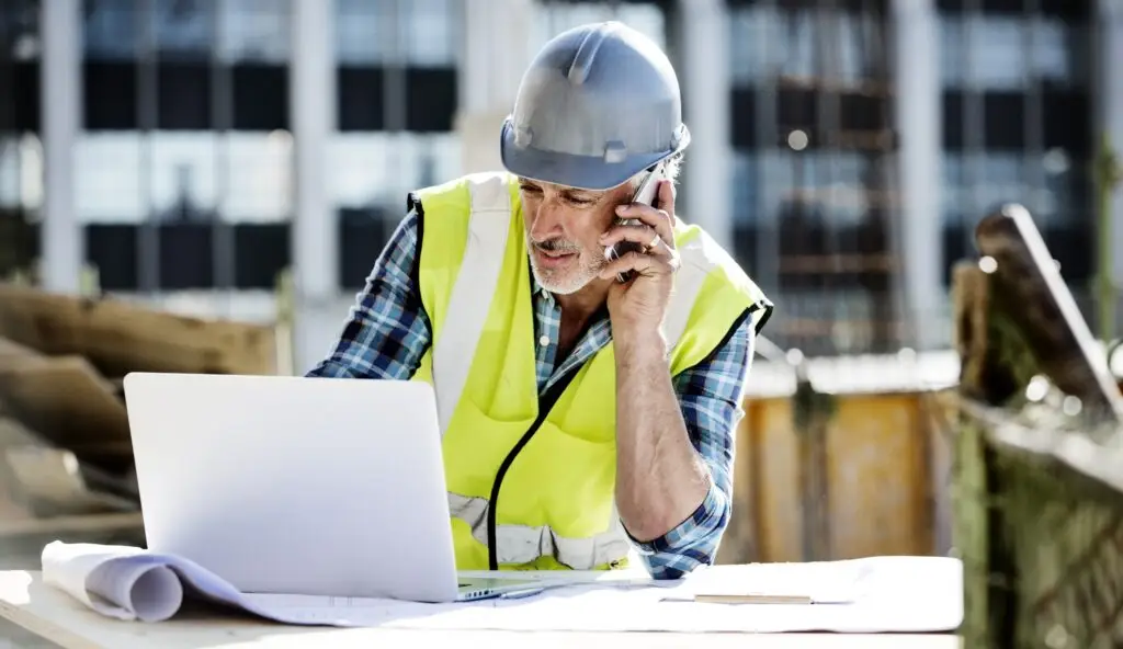 man on looking at computer on his cell phone at a job site